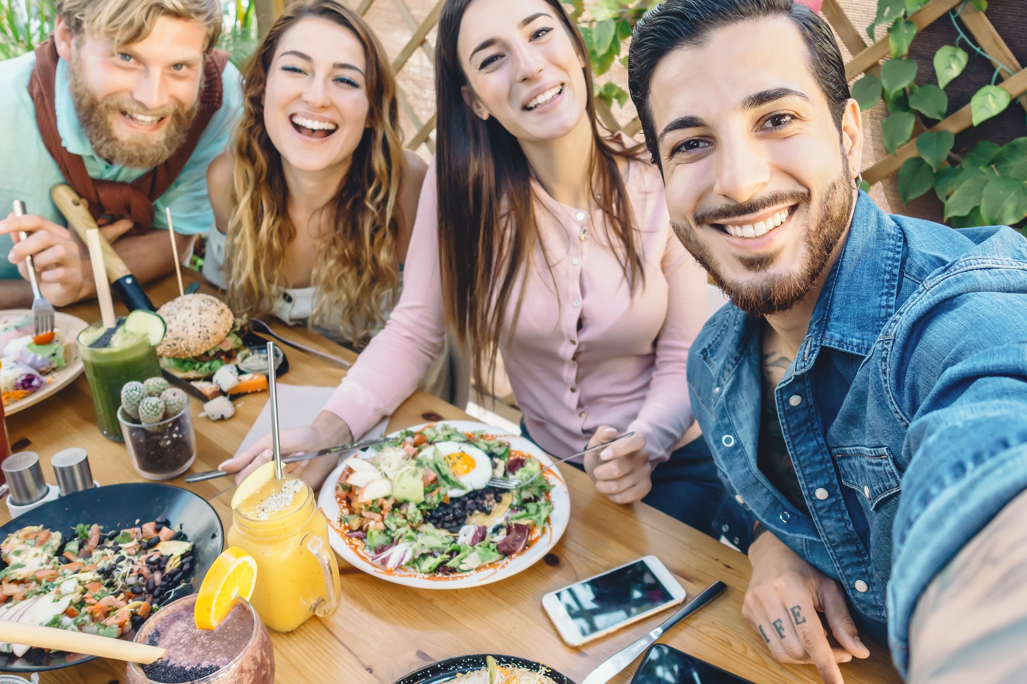 Happy friends taking selfie with mobile smartphone while lunching in coffee brunch restaurant